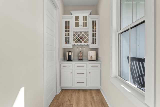 bar with white cabinetry and light wood-type flooring