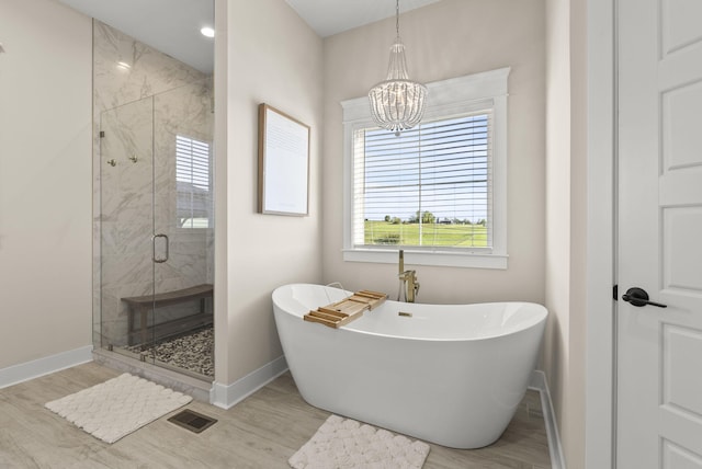 bathroom with hardwood / wood-style floors, shower with separate bathtub, and an inviting chandelier