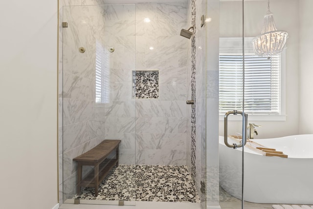 bathroom with a notable chandelier and shower with separate bathtub