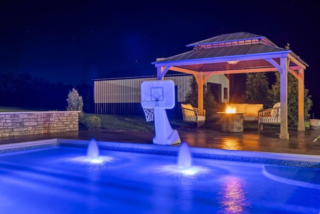 pool at night featuring a gazebo