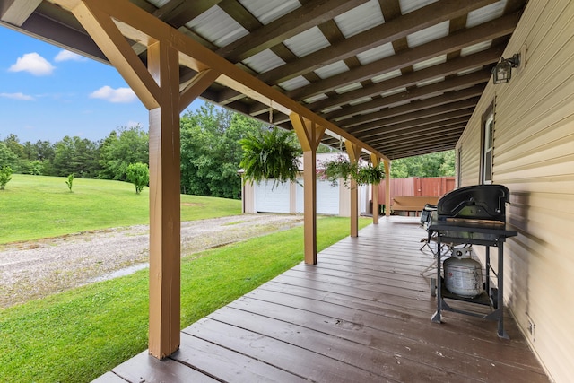 wooden deck featuring grilling area, a garage, and a lawn