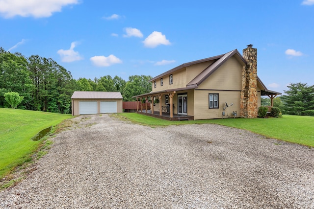 view of front of property with covered porch, a front yard, an outbuilding, and a garage