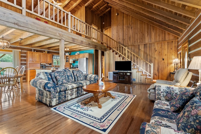 living room featuring hardwood / wood-style flooring, wooden walls, a chandelier, and high vaulted ceiling