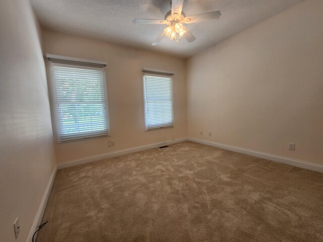 unfurnished room featuring light carpet, ceiling fan, and a textured ceiling