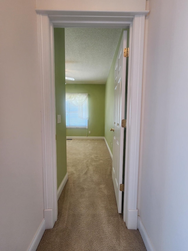 corridor with light colored carpet and a textured ceiling