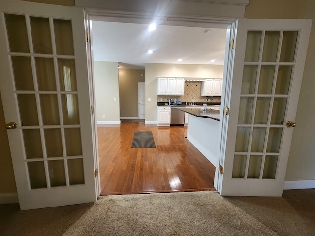 kitchen featuring tasteful backsplash, sink, white cabinets, light hardwood / wood-style flooring, and stainless steel dishwasher