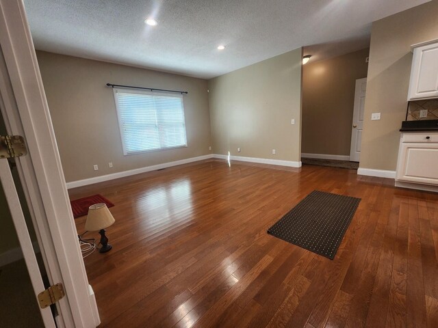 unfurnished living room featuring wood-type flooring and a textured ceiling