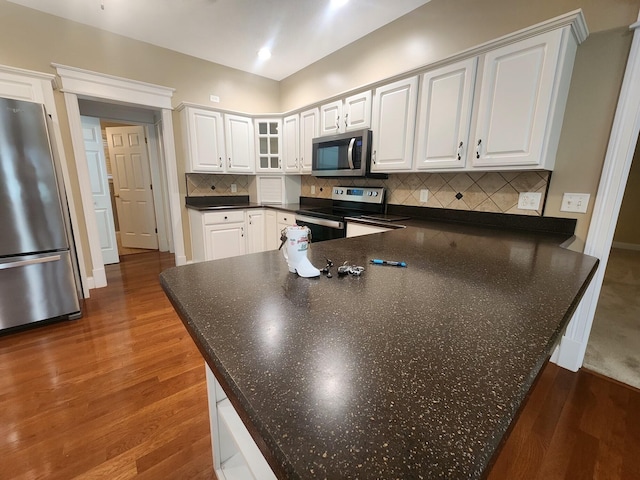 kitchen featuring decorative backsplash, white cabinetry, appliances with stainless steel finishes, and dark hardwood / wood-style floors