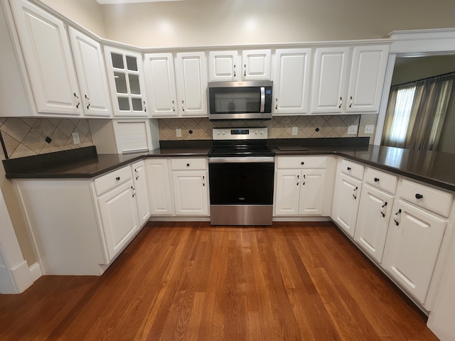 kitchen featuring decorative backsplash, dark wood-type flooring, stainless steel appliances, and white cabinets