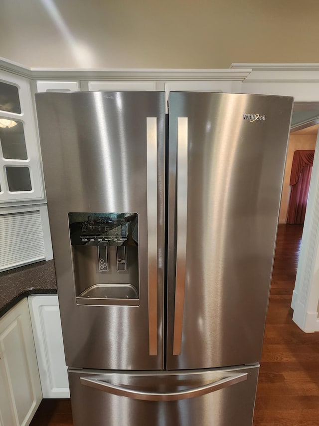 interior details with stainless steel fridge, dark wood-type flooring, and white cabinets