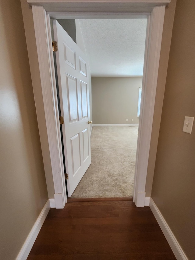 hall featuring a textured ceiling and dark hardwood / wood-style floors