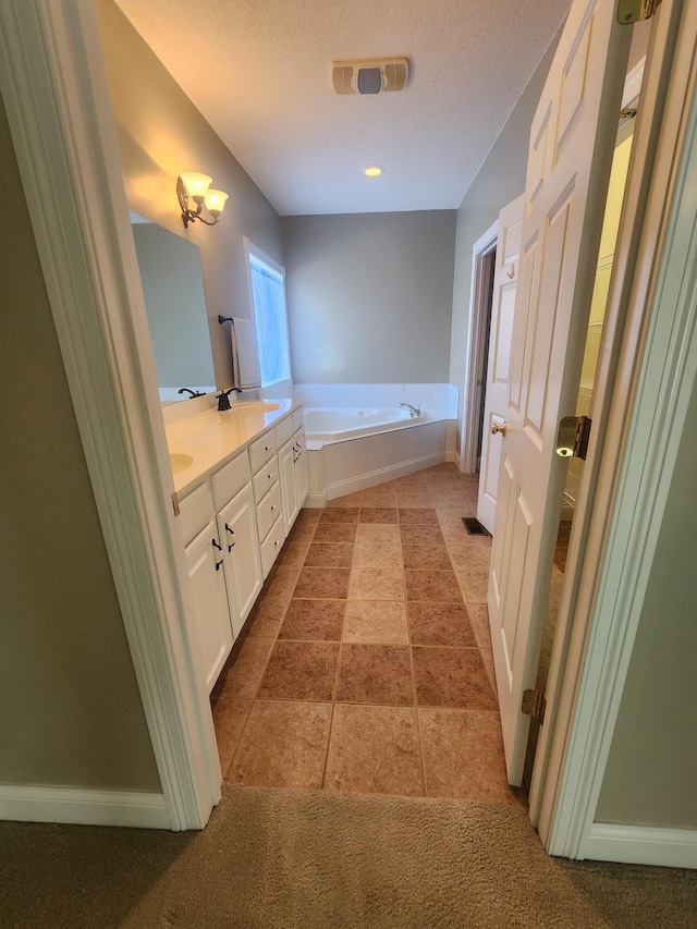 bathroom featuring a textured ceiling, tile patterned flooring, vanity, and a tub