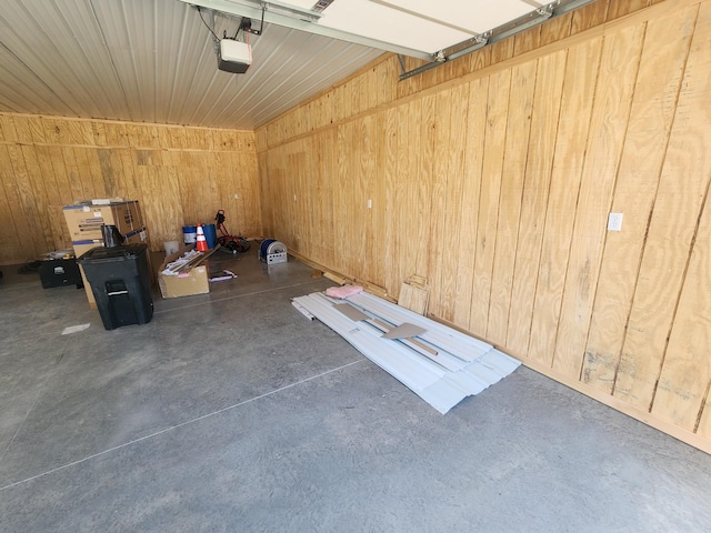 garage with a garage door opener and wood walls