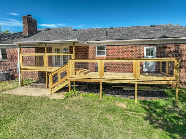 rear view of property with cooling unit, a shingled roof, a yard, a wooden deck, and a chimney