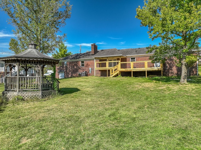 back of house with brick siding, a yard, a chimney, a gazebo, and a wooden deck