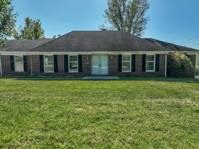 single story home featuring roof with shingles, a front yard, and brick siding