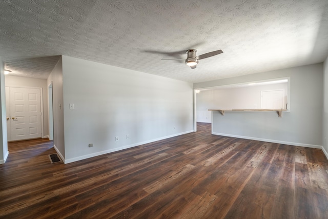 unfurnished living room with dark wood-style floors, visible vents, ceiling fan, and baseboards