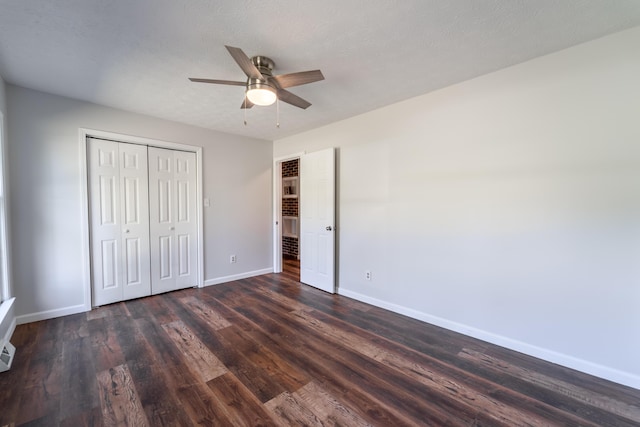 unfurnished bedroom featuring ceiling fan, a textured ceiling, wood finished floors, baseboards, and a closet