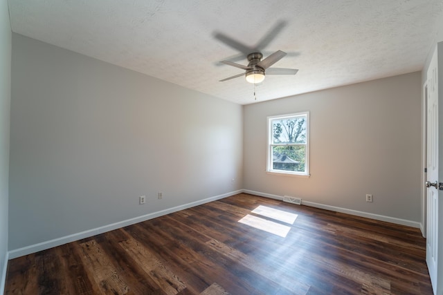 empty room with a textured ceiling, dark wood-type flooring, visible vents, and baseboards