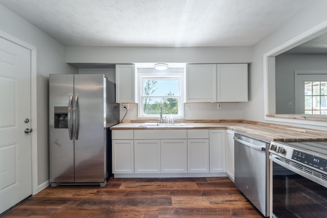 kitchen with dark wood-type flooring, white cabinetry, stainless steel appliances, and a textured ceiling