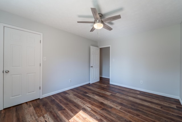 empty room featuring dark wood-style floors, baseboards, and a ceiling fan