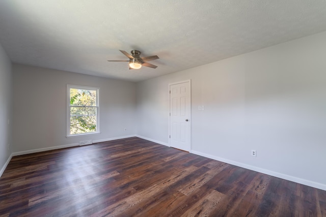 spare room featuring a textured ceiling, dark wood-style flooring, a ceiling fan, and baseboards