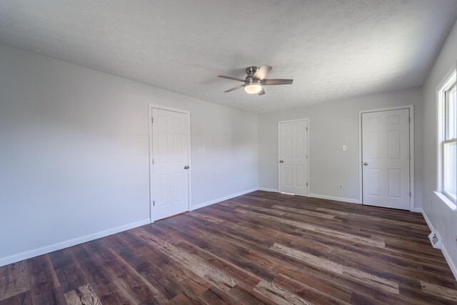 spare room with ceiling fan, a wealth of natural light, dark hardwood / wood-style floors, and a textured ceiling