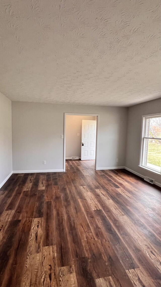 unfurnished room with ceiling fan, a textured ceiling, and dark hardwood / wood-style floors