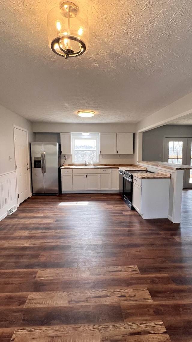 kitchen featuring black range with electric cooktop, dark wood finished floors, stainless steel refrigerator with ice dispenser, and a peninsula