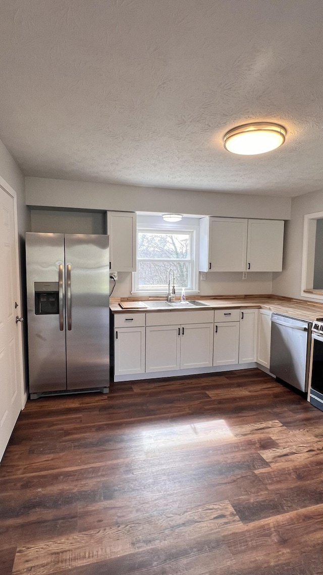 kitchen featuring appliances with stainless steel finishes, white cabinetry, a sink, and dark wood-style floors