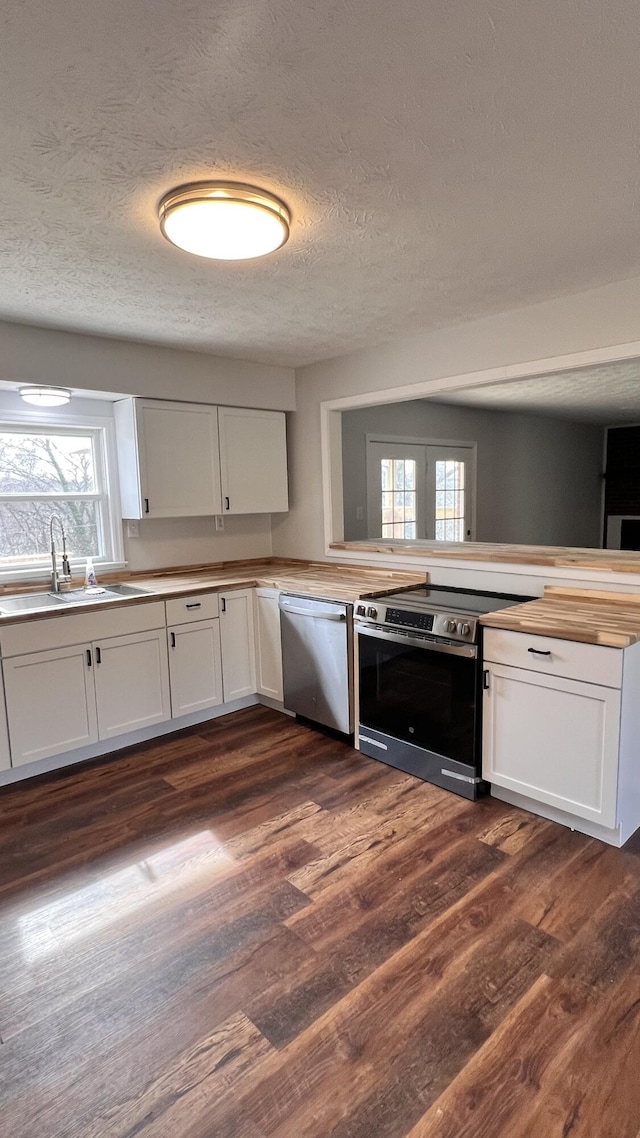 kitchen with stainless steel appliances, dark wood-style flooring, wood counters, a sink, and white cabinetry