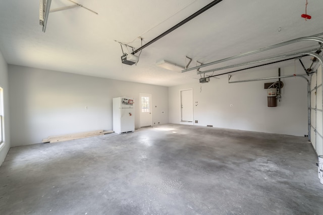 garage with a garage door opener and white refrigerator