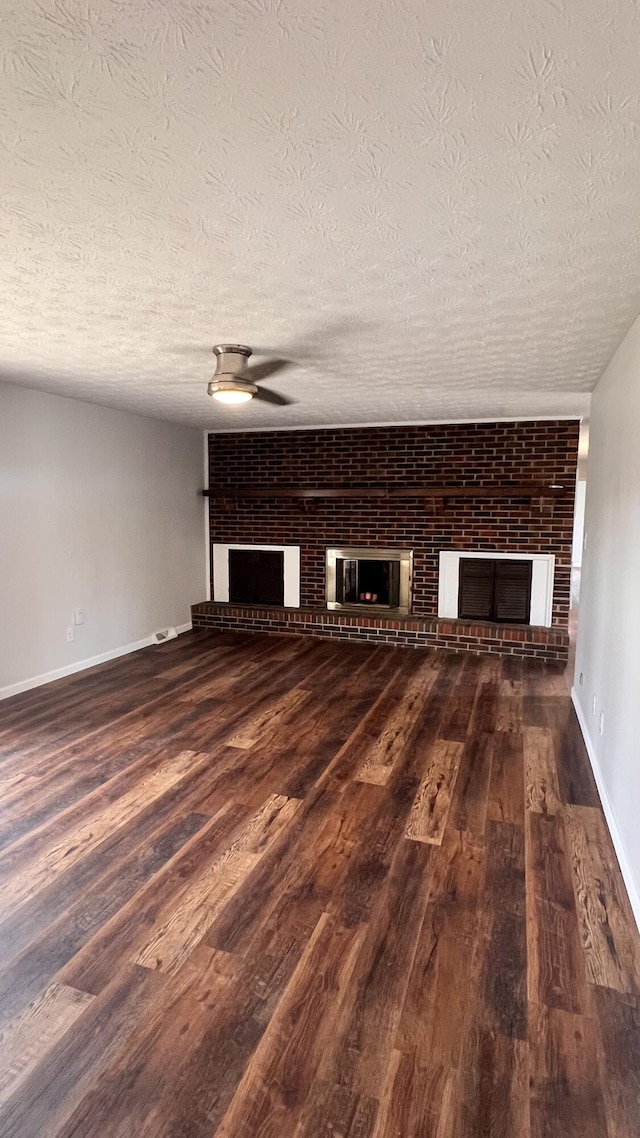 unfurnished living room with a brick fireplace, baseboards, a ceiling fan, and wood finished floors