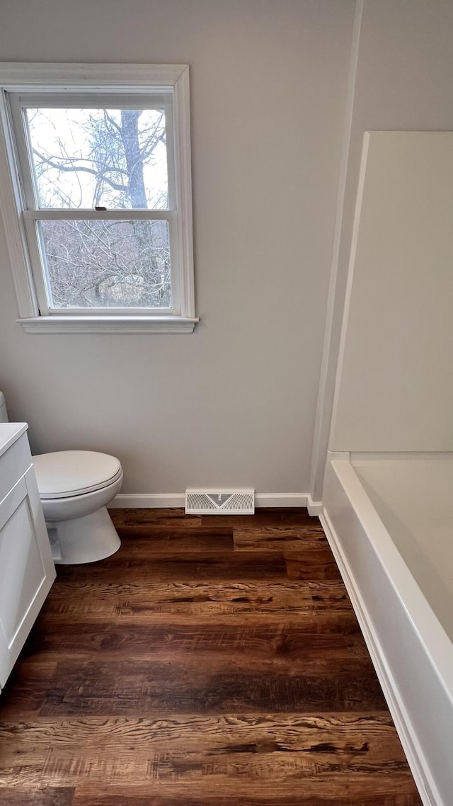 full bathroom with toilet, baseboards, visible vents, and wood finished floors