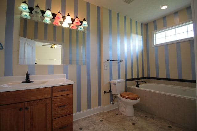 bathroom with tiled tub, vanity, and toilet