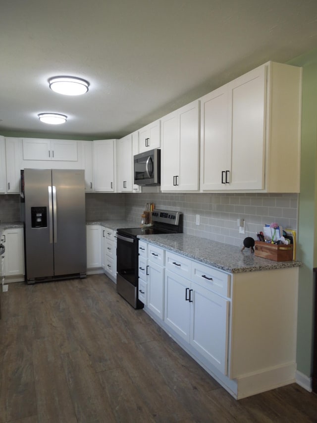 kitchen featuring tasteful backsplash, dark wood-style flooring, light stone countertops, stainless steel appliances, and white cabinetry