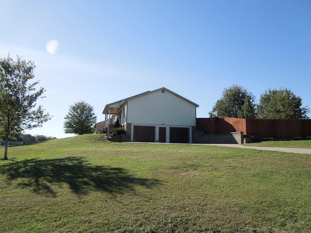 exterior space with driveway, a garage, fence, and a yard