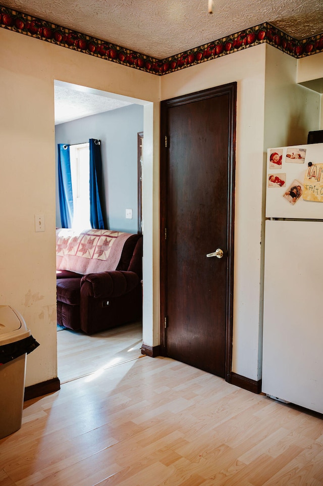 corridor with light hardwood / wood-style floors and a textured ceiling