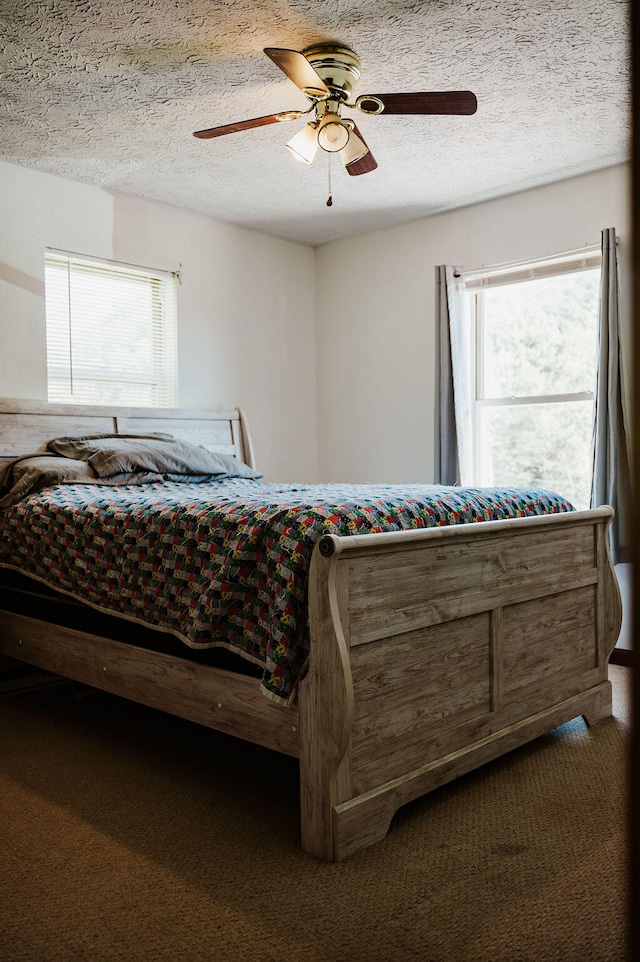 bedroom featuring ceiling fan, dark carpet, and multiple windows