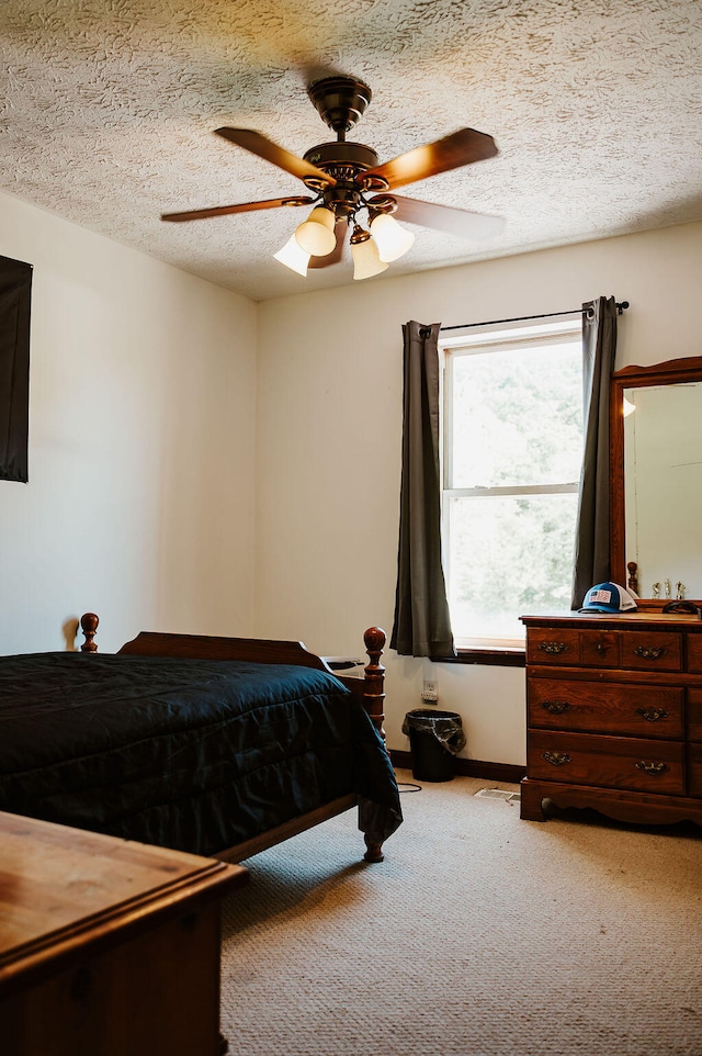 bedroom with a textured ceiling, ceiling fan, and carpet floors