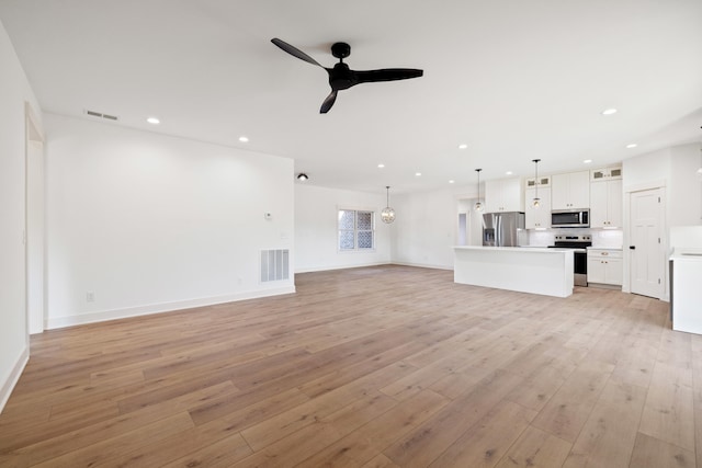 unfurnished living room featuring light wood-type flooring and ceiling fan with notable chandelier