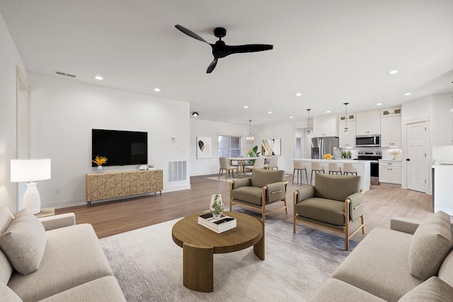 living room with ceiling fan and light hardwood / wood-style flooring