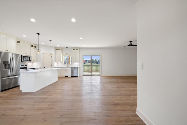 kitchen with a center island, decorative light fixtures, stainless steel appliances, and light hardwood / wood-style floors