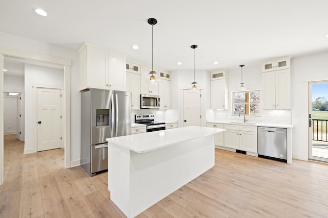 kitchen with a kitchen island, appliances with stainless steel finishes, white cabinetry, and light hardwood / wood-style floors