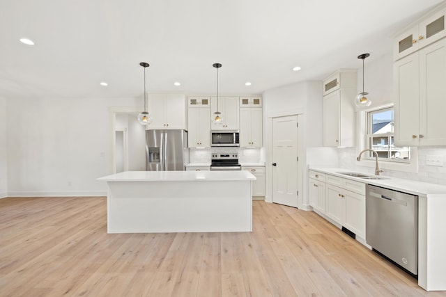 kitchen with a center island, white cabinetry, stainless steel appliances, and sink