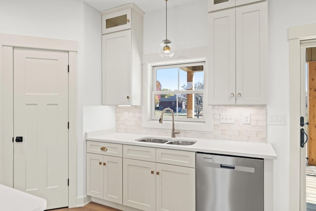 kitchen with decorative backsplash, white cabinets, dishwasher, sink, and decorative light fixtures