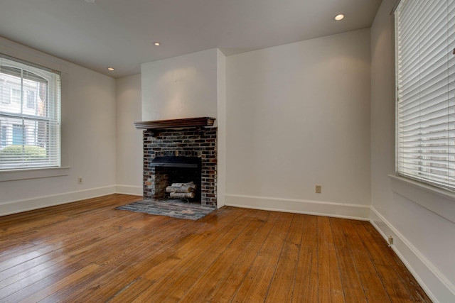 unfurnished living room with hardwood / wood-style flooring and a brick fireplace