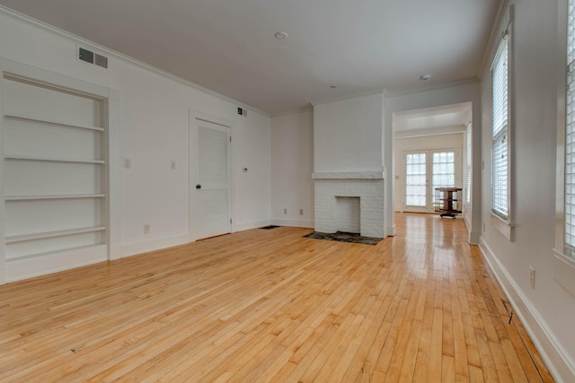 unfurnished living room with a fireplace, built in shelves, light hardwood / wood-style floors, and ornamental molding