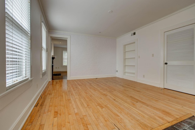 spare room featuring light wood-type flooring, built in features, and ornamental molding