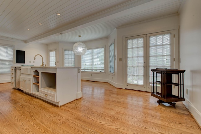 kitchen featuring white cabinetry, pendant lighting, light wood-type flooring, a kitchen island with sink, and ornamental molding